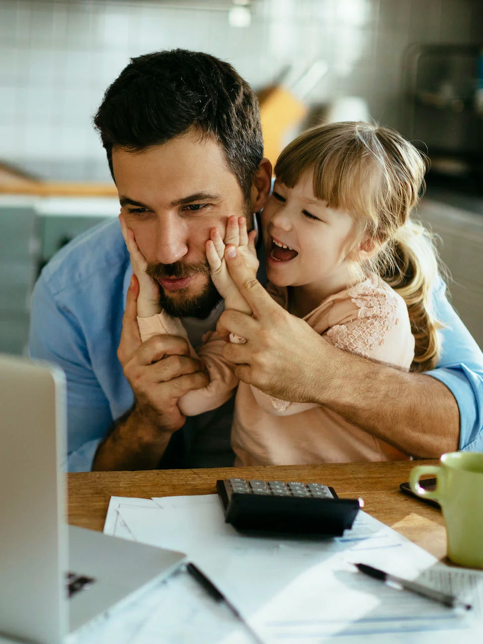 Father working on finances while entertaining his daughter